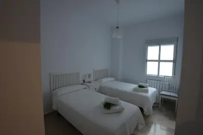a white room with two beds and a window at PLAZA ALFONSO SÁNCHEZ FERRAJÓN in Jerez de la Frontera