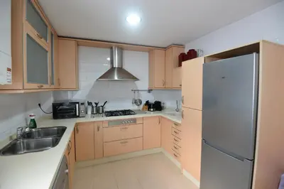 a kitchen with wooden cabinets and a stainless steel refrigerator at PLAZA ALFONSO SÁNCHEZ FERRAJÓN in Jerez de la Frontera