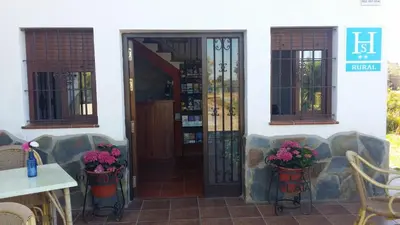 an open door of a house with flowers in buckets at Hostal Rural La Plata Parking Incluido in Arcos de la Frontera