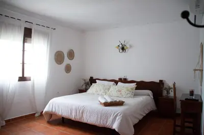 a bedroom with a bed with white sheets and a window at Hostal Rural La Plata Parking Incluido in Arcos de la Frontera