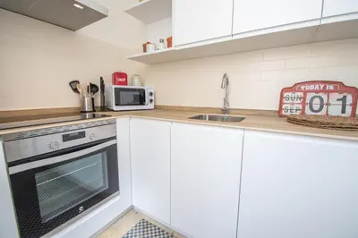 a kitchen with white cabinets and a sink and a microwave at Apartamentos Las Musas de Cadiz in Cádiz