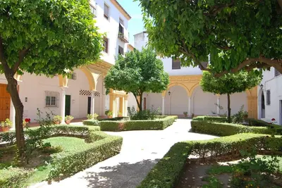 a courtyard of a building with trees and bushes at El Rincon de Elena (Garden Apartment) in Jerez de la Frontera