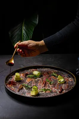 a person holding a spoon over a pizza on a table at Boutique Hotel OLOM - Only Adults recommended in Cádiz