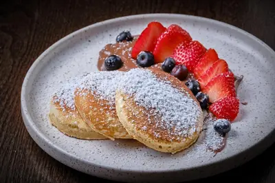 a plate of pancakes with strawberries and blueberries at Boutique Hotel OLOM - Only Adults recommended in Cádiz