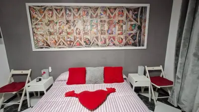 a bedroom with a bed with red pillows and chairs at A 50 metros de la playa in Cádiz