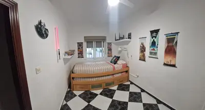 a small bedroom with a bed and a checkered floor at A 50 metros de la playa in Cádiz