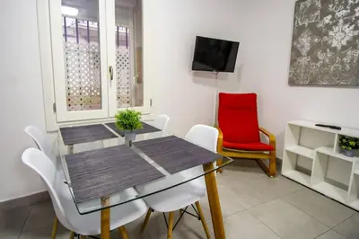 a dining room with a table and a red chair at SH Cruz. Moderno apartmento cerca del Mercado. in Cádiz