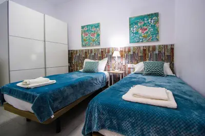 two beds in a room with blue sheets at SH Cruz. Moderno apartmento cerca del Mercado. in Cádiz
