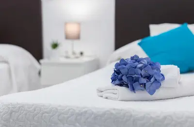 a white bed with a blue flower on top of it at El Balneario in Cádiz