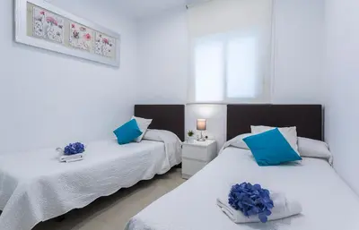 two beds in a room with blue pillows on them at El Balneario in Cádiz