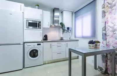 a kitchen with a washer and dryer and a table at El Balneario in Cádiz