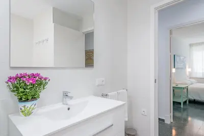 a white bathroom with a sink and a vase of flowers at Sherryflat Casa del Arquitecto in Jerez de la Frontera