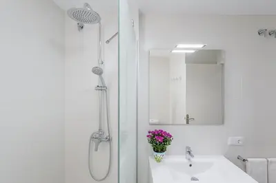 a white bathroom with a sink and a shower at Sherryflat Casa del Arquitecto in Jerez de la Frontera
