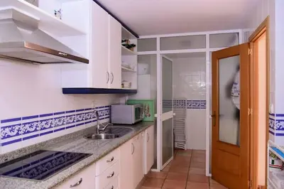 a kitchen with white cabinets and a sink at Charming house in Rota + garden in Rota