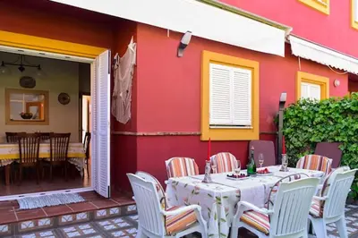 a table and chairs in front of a red house at Charming house in Rota + garden in Rota