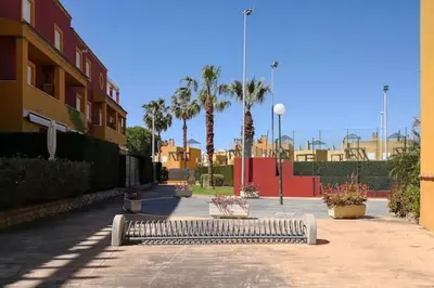 a bench in a courtyard with palm trees and buildings at Charming house in Rota + garden in Rota