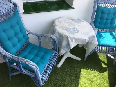 two blue wicker chairs and a table with a table at Luminoso apartamento en playa las redes, entorno natural pinares y dunas. Wifi in El Puerto de Santa María
