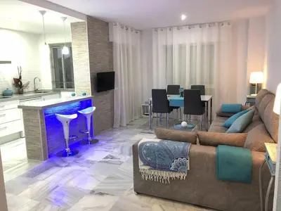 a living room with a couch and a dining room at Luminoso apartamento en playa las redes, entorno natural pinares y dunas. Wifi in El Puerto de Santa María