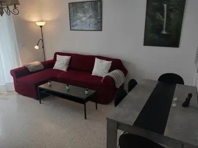 a living room with a red couch and a table at Apartamento acogedor en lugar inmejorable in Sanlúcar de Barrameda