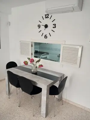 a dining room table with chairs and a clock on the wall at Apartamento acogedor en lugar inmejorable in Sanlúcar de Barrameda