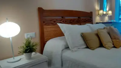 a bedroom with a white bed with pillows and a lamp at Charming apartment in El Puerto de Santa María with terrace in El Puerto de Santa María