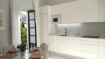 a kitchen with white cabinets and a glass table at Sherryflat San Agustín in Jerez de la Frontera