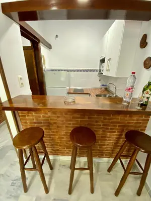 a kitchen with a wooden counter and two stools at Castillo del Espiritu Santo (La Jara) in Sanlúcar de Barrameda