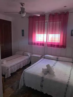 two beds in a room with pink curtains at El Mirador de la Playa Cortadura Grupo AC Gestion in Cádiz