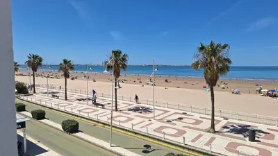 a view of a beach with palm trees and people at TU DENSCANSO EN VALDELAGRANA FRENTE AL MAR in El Puerto de Santa María