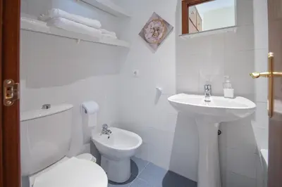 a white bathroom with a toilet and a sink at Apartment Cadiz´s Angel in Cádiz
