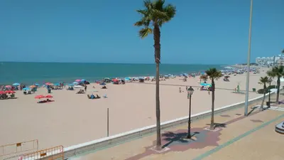 a group of people on a beach with the ocean at Los luceros in Rota