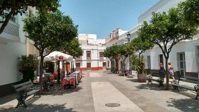 an empty street with tables and chairs and trees at Los luceros in Rota