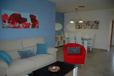 a living room with a couch and a red chair at Apartamento Costa Ballena in Chipiona