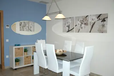 a dining room with a glass table and white chairs at Apartamento Costa Ballena in Chipiona