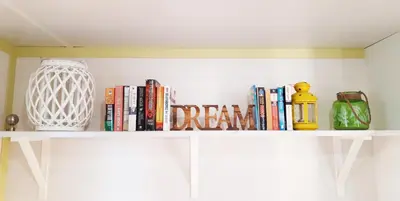 a white shelf with books and a vase and books at The PineForest Cabin in Chiclana de la Frontera