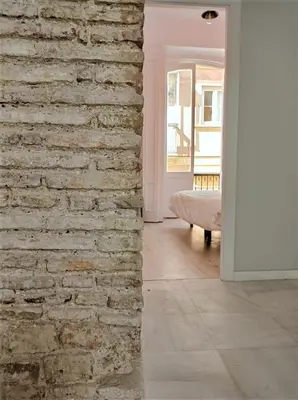 a brick wall in a living room with a bed at Planeta Cadiz Hostel in Cádiz