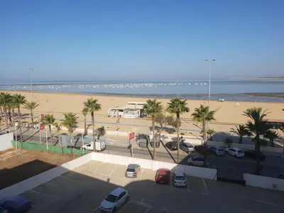 a parking lot next to a beach with palm trees at PISO 1ª LINEA SANLUCAR DE BARRAMEDA in Sanlúcar de Barrameda