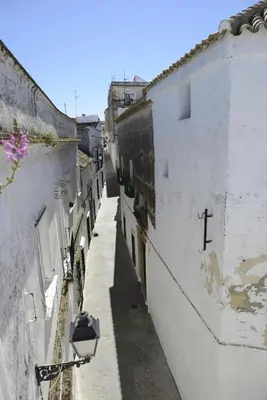 an alley with white buildings and a cross on the side at Casa Rural Las Cadenas del Cananeo in Arcos de la Frontera