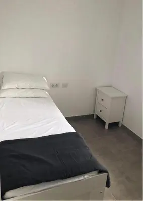 a bedroom with a white bed and a night stand at Apartamento Gran Teatro Falla-La Caleta in Cádiz