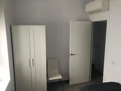 a bedroom with a white cabinet and a chair at Apartamento Gran Teatro Falla-La Caleta in Cádiz