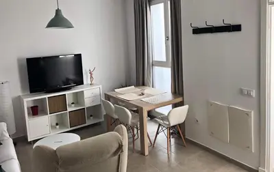 a living room with a table with chairs and a television at Apartamento Gran Teatro Falla-La Caleta in Cádiz