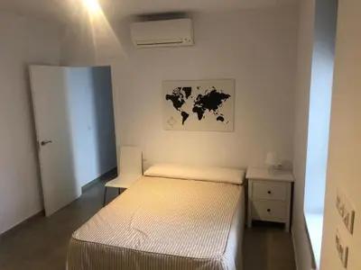a small bedroom with a bed and a night stand at Apartamento Gran Teatro Falla-La Caleta in Cádiz