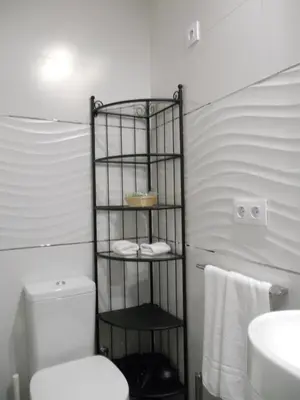 a bathroom with a towel rack next to a toilet at Santa María 12 Boutique Apartamentos in Cádiz