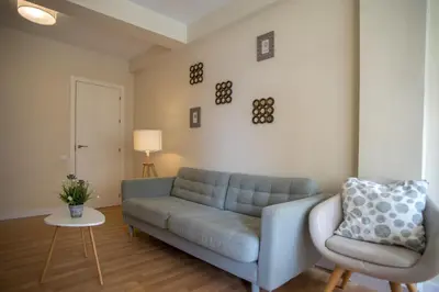 a living room with a blue couch and a chair at Sirenas Playa Ha Apartment in Cádiz