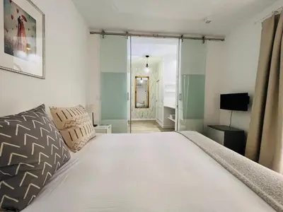 a bedroom with a large white bed and a television at Chipibeach B&B, Hostal Boutique in Chipiona
