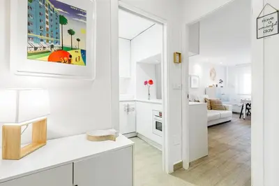 a white kitchen with white cabinets and a living room at Casa Brasil - 1ª Linea Playa con Parking Incluido in Cádiz