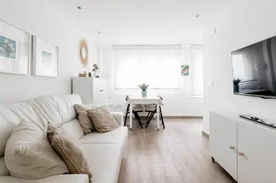 a white living room with a white couch and a table at Casa Brasil - 1ª Linea Playa con Parking Incluido in Cádiz