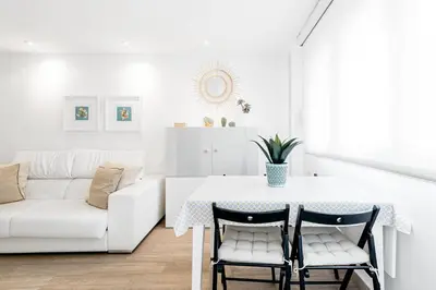 a white living room with a table and a couch at Casa Brasil - 1ª Linea Playa con Parking Incluido in Cádiz
