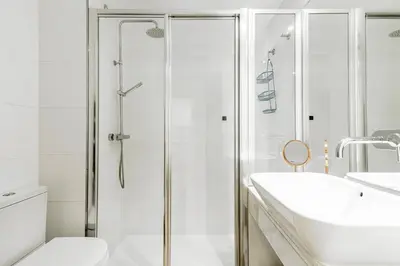 a white bathroom with a shower and a sink at Casa Brasil - 1ª Linea Playa con Parking Incluido in Cádiz