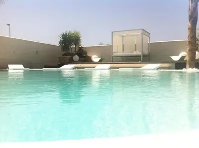a swimming pool with blue water in front of a building at Villa Campito in El Puerto de Santa María